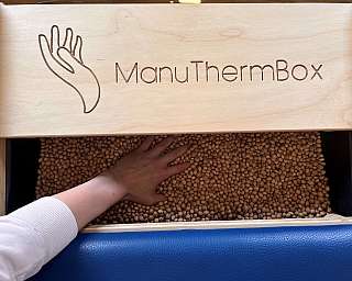 Zwei Personen in einem Raum mit therapeutischem Gerät und Materialien.