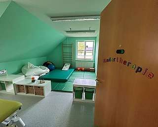 Zwei Frauen interagieren mit einem Holzspielgerät und bunten Ringen.