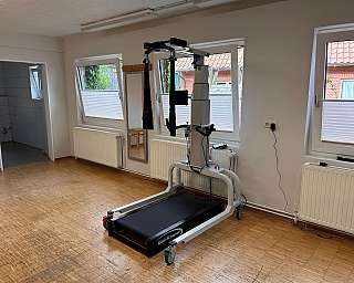 Eine Person sitzt auf einem Gymnastikball, während eine Therapeutin assistiert.
