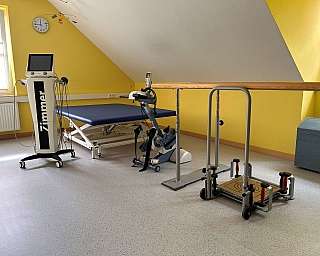 Eine Person sitzt auf einem Gymnastikball, während eine Therapeutin assistiert.