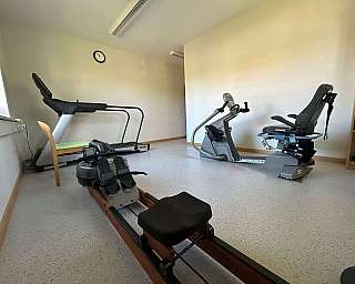 Eine Person nutzt ein Fitnessgerät mit Anleitung einer Trainerin.