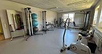 Eine Person nutzt ein Fitnessgerät unter Anleitung einer Trainerin.