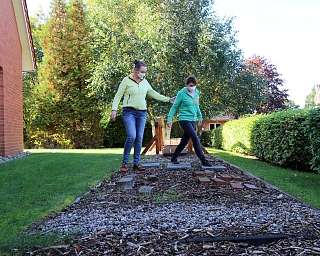 Zwei Frauen gehen auf einem Steg im Garten.